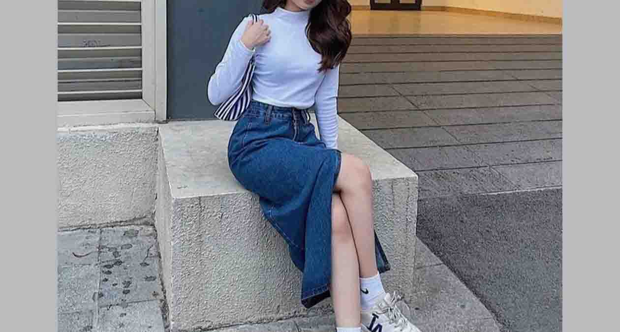 دختری با دامن جین بلند به رنگ آبی تیره به همراه تیشرت سفید