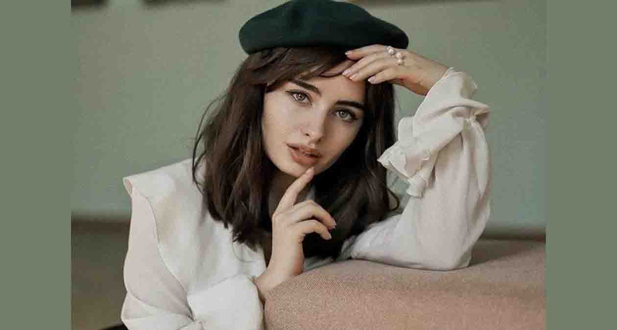 زنی با بلوز سفید و کلاه سبز